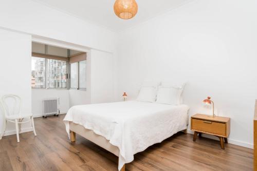 a white bedroom with a white bed and a table at Lovely 2 Bedroom Apartment in Caparica in Almada