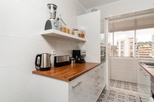 a kitchen with white walls and a wooden counter top at Lovely 2 Bedroom Apartment in Caparica in Almada