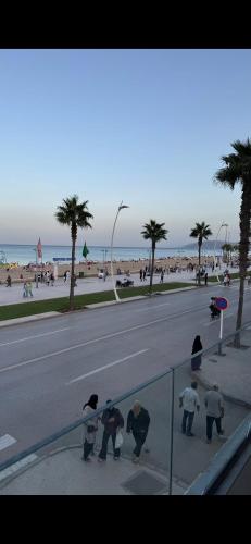 a group of people standing on a sidewalk near the beach at appartement pieds dans l'eau in Martil
