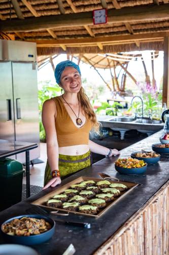 a woman standing behind a counter with a tray of food at Eco Luxe Glamping Tent - King Bed at Holos in Barú