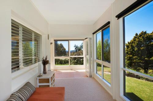 a living room with large windows and a couch at St Raphael in Leura