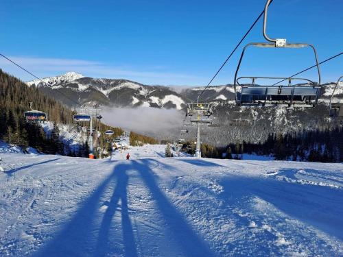 a shadow of a ski lift on a snow covered slope at Rezort pod Roháčmi in Vitanová