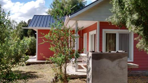 une petite maison rouge avec un jardin en face de celle-ci dans l'établissement Estancia Río Abajo, à Trevelín