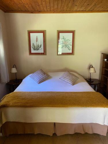 a bedroom with a large bed with two pictures on the wall at Hotel Fazenda São Francisco in Cunha