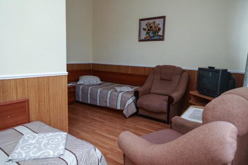 a room with a bed and a tv and chairs at Карпаты in Khust