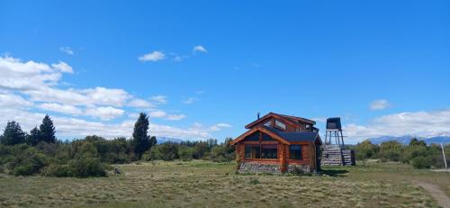 a small wooden house in a field with a chair at Los Trevelinos in Trevelin