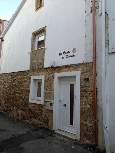 a white building with a door on the side of it at Ao Carón do Camiño in Padrón