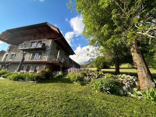 ein Haus mit einem Baum und Blumen davor in der Unterkunft Les Chanterelles Montmin in Plan Motmin