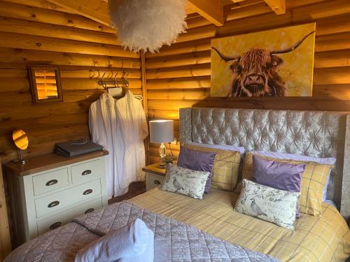 a bedroom with a bed with a cow picture on the wall at The Farmers den lodge at River Garry Lodges in Bridge of Tilt