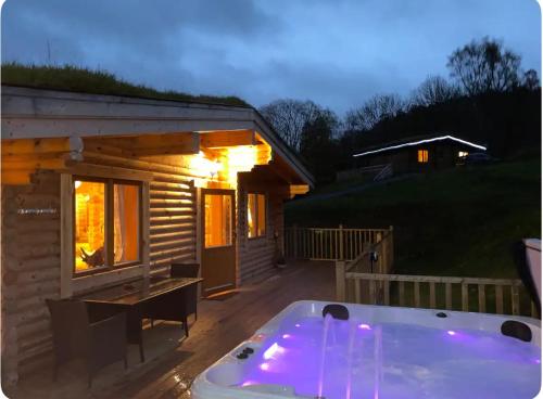 a hot tub in front of a log cabin at The Farmers den lodge at River Garry Lodges in Bridge of Tilt