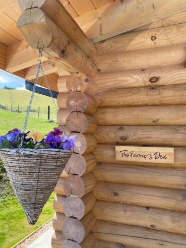 a sign on a wooden wall with a basket of flowers at The Farmers den lodge at River Garry Lodges in Bridge of Tilt
