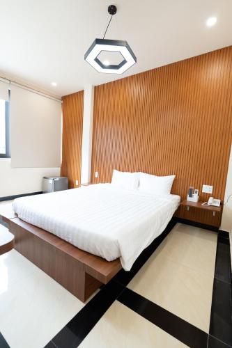 a bedroom with a large bed with a wooden wall at ARA Gem Hotel in Ho Chi Minh City