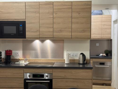 une cuisine avec des armoires en bois et un four à plaques de cuisson dans l'établissement Presqu'ile Saint Nizier coeur de Lyon classé 4*, à Lyon