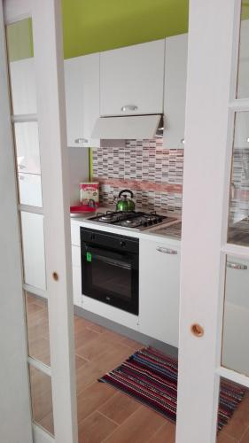 a kitchen with white cabinets and a stove top oven at Donkey on the Beach in Cobbs Cross