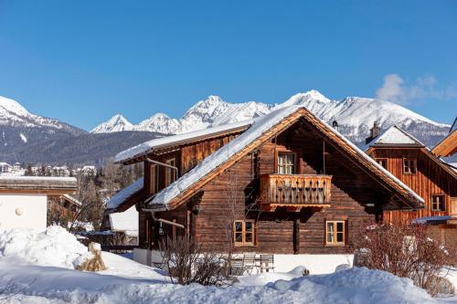 a log cabin in the snow with mountains in the background at Alm Chalet Grosseck in Mariapfarr