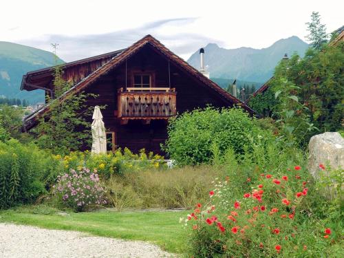 a wooden house with a balcony in a garden at Alm Chalet Grosseck in Mariapfarr