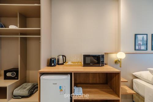 a small kitchen with a microwave and a refrigerator at MHFA - Studios em Prédio Luxuoso com Vista Mar in Itapema