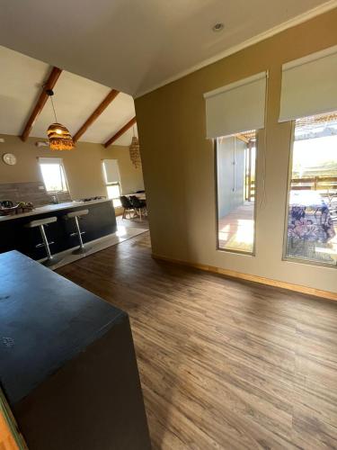 an empty living room with wooden floors and windows at Refugio Rivarahi in Hanga Roa