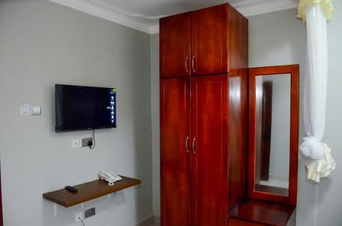 a living room with a tv and a red cabinet at Big Thrills Hotel and Suites Kampala in Kampala