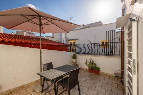 a table and chairs with an umbrella on a balcony at Antiche Mura Apartments "Nel Cuore della Puglia"bivani, cucina, terrazzo in Turi