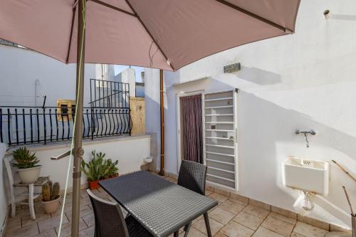 a table and chairs on a balcony with an umbrella at Antiche Mura Apartments "Nel Cuore della Puglia"bivani, cucina, terrazzo in Turi