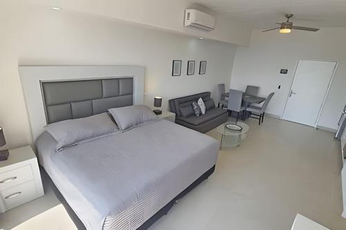 Un dormitorio con una cama grande y una sala de estar. en Costa Paraíso Estudio D-21, en Bucerías