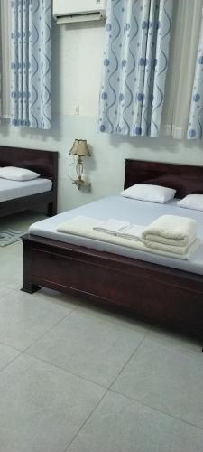 a bedroom with two beds and a lamp in it at Nhà Nghỉ Khá Thuận - phòng đôi in Ấp Châu Thới