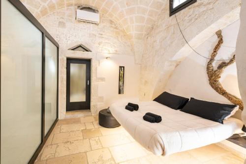 a bedroom with a large white bed with black pillows at Rifugio Del Monsignore in Ostuni
