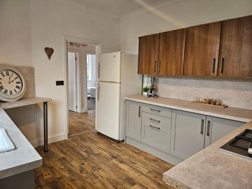 Una cocina con refrigerador blanco y gabinetes de madera. en The White Bungalow, en Boughton