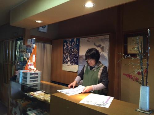 Eine Frau, die an einem Tresen in einem Laden steht. in der Unterkunft Yudanaka Onsen Yamazakiya in Yamanouchi