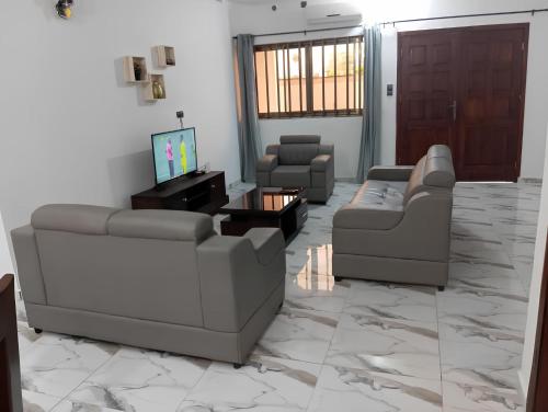a living room with two couches and a tv at Superbe Appartement COTONOU CENTRE VILLE entre Place de L'étoile Rouge et vedoko in Cotonou