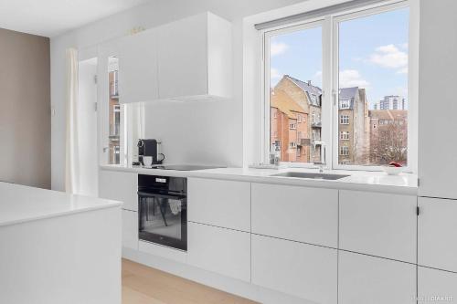 a kitchen with white cabinets and a window at Bright & Inviting Apartment Near ARoS Art Museum in Aarhus