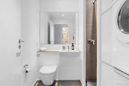 a white bathroom with a toilet and a sink at Bright & Inviting Apartment Near ARoS Art Museum in Aarhus