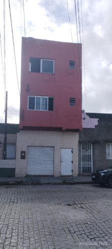 a pink building with windows and a car parked in front at Pousada Paradise in Rio Grande