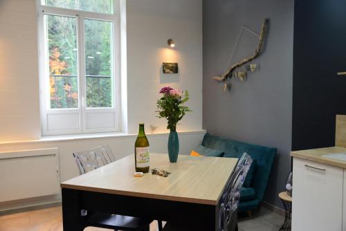 - une table avec une bouteille de vin et un vase dans l'établissement L' Empesson, à Clairvaux-les-Lacs