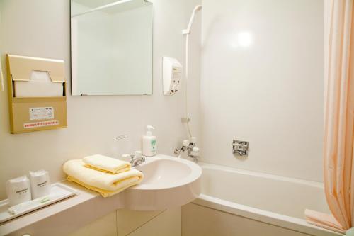 Baño blanco con lavabo y espejo en Hotel Folkloro Kakunodate, en Senboku
