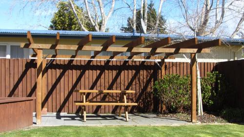 a wooden picnic table under a wooden pergola at Bella Vista Motel Te Anau in Te Anau
