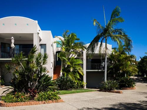 a white house with palm trees in front of it at The Point Coolum in Coolum Beach