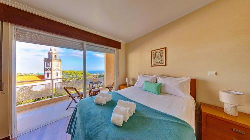 una camera con un letto e una finestra con una torre dell'orologio di Caniço Zentrum Wohnung a Caniço