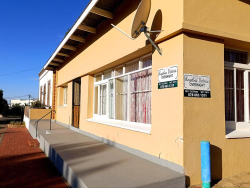 a yellow building with signs on the side of it at Angelina Victoria Overnight in Colesberg
