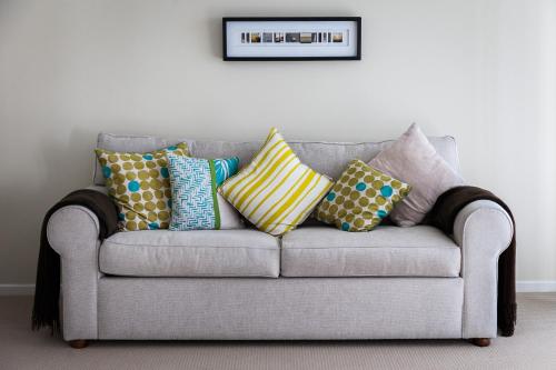 a gray couch with colorful pillows on it at The Point Coolum in Coolum Beach