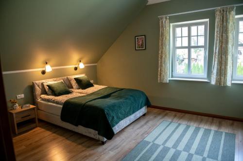 a bedroom with a bed and two windows at Pensjonat Jutrzenka in Spychowo