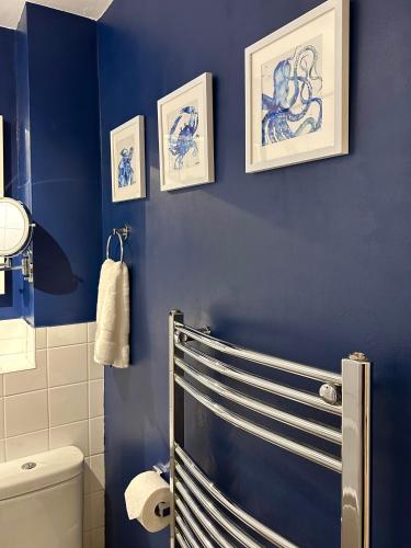 a blue bathroom with a toilet and three pictures on the wall at Northern Line Studio Stay with Free Parking in Mitcham