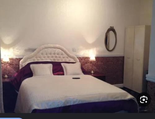 une chambre avec un lit blanc et un miroir dans l'établissement Number 10, à Blackpool