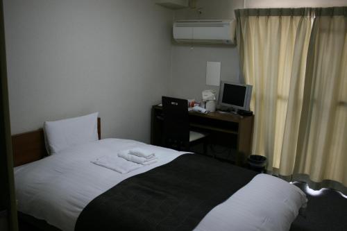 a bedroom with a bed and a desk with a computer at HOTEL CITY INN WAKAYAMA Wakayama-Ekimae in Wakayama