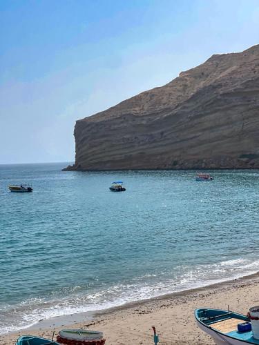 a beach with boats in the water next to a mountain at Otium2 in Qantab