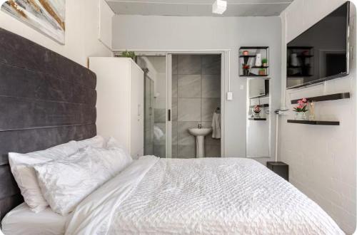 a bedroom with a white bed and a bathroom at A Room with private Entrance in Cape Town