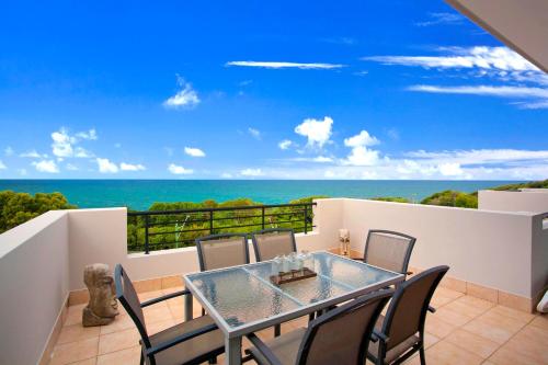 a table and chairs on a balcony with the ocean at The Point Coolum in Coolum Beach