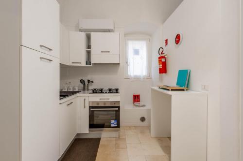 a kitchen with white cabinets and a laptop on a counter at Antiche Mura Apartments"Bianco di Puglia" cucina 1 camera da letto più divano letto in Turi