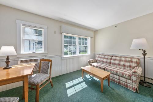 a living room with a couch and a table and two windows at Country Inn at Camden Rockport in Rockport